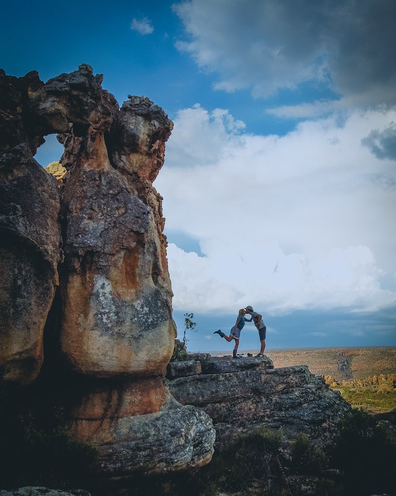 a couple kissing next to rocks